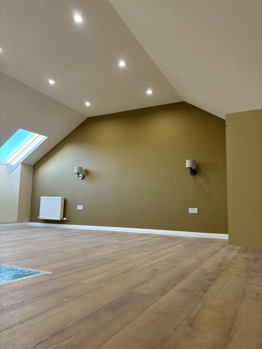 Attic after conversion — Wicklow. Finished attic room with warm tones, timber floor and skylights.