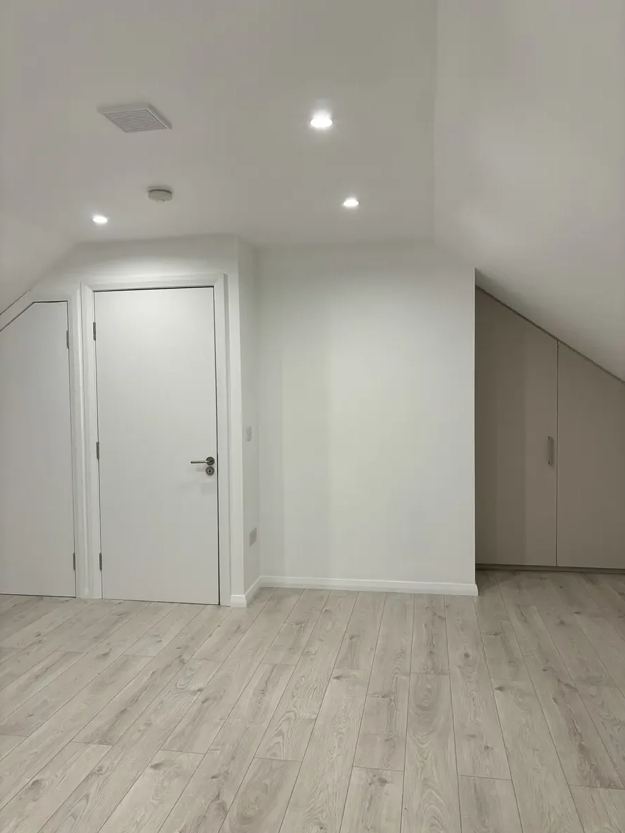 Attic conversion — Citywest, Dublin. Fitted white storage with timber accent wall.